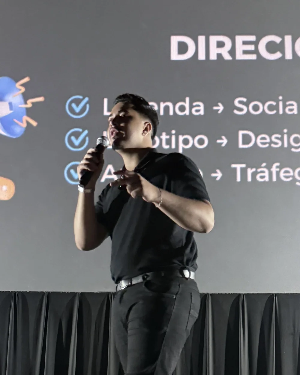 Kaio Gomes palestrando no palco, de microfone na mão